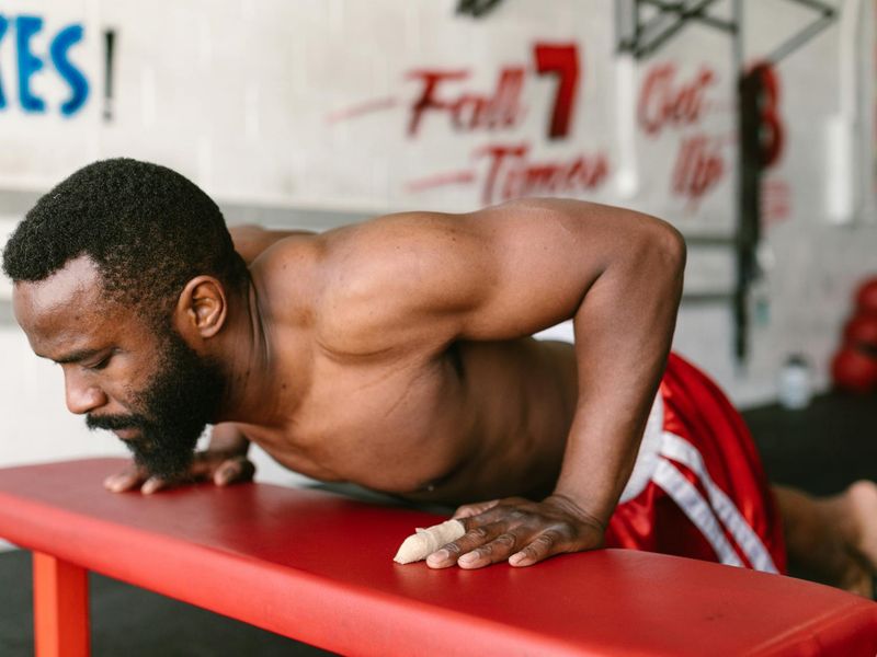 Man performing a controlled bodyweight exercise in a minimalist gym setting.